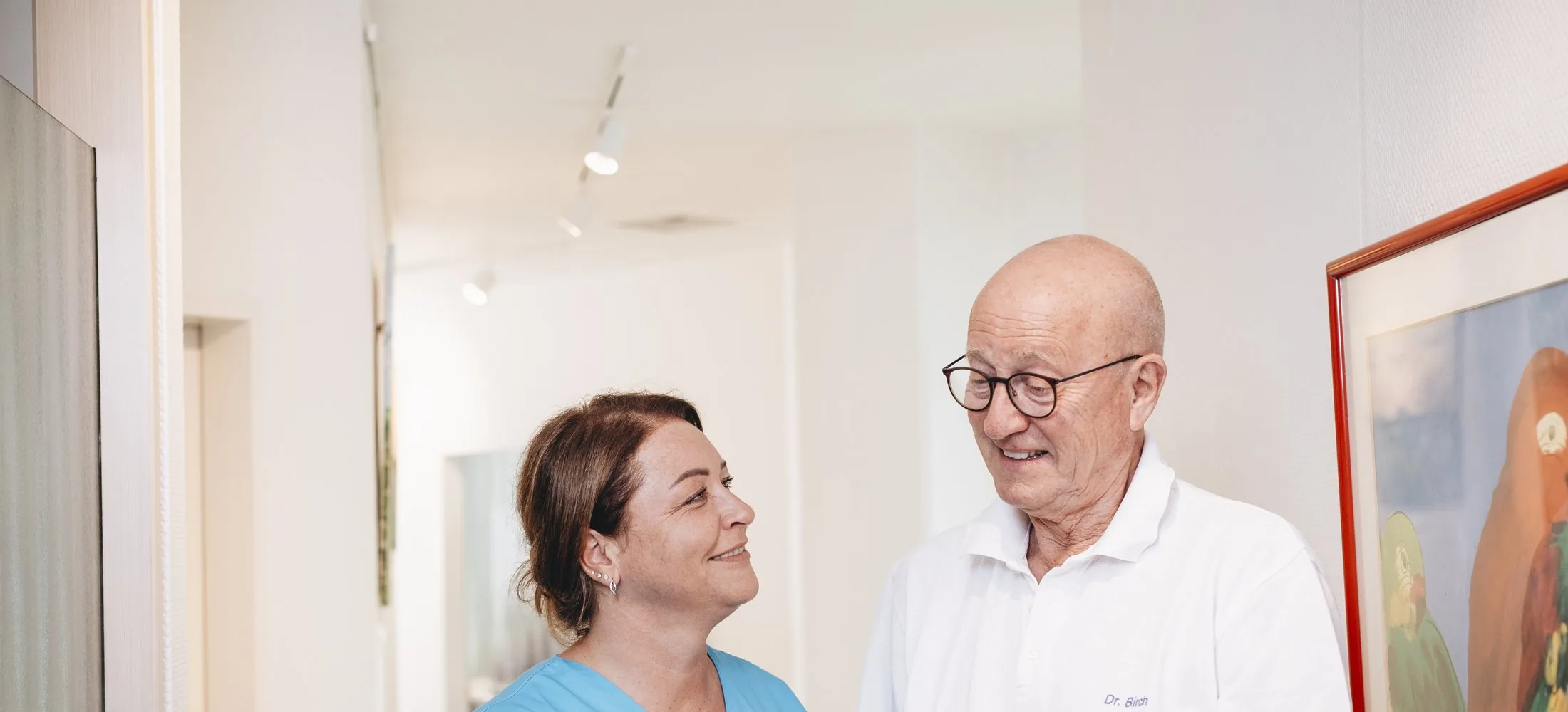 Dr. Birch im Gespräch mit einer Mitarbeiterin auf dem Praxisflur